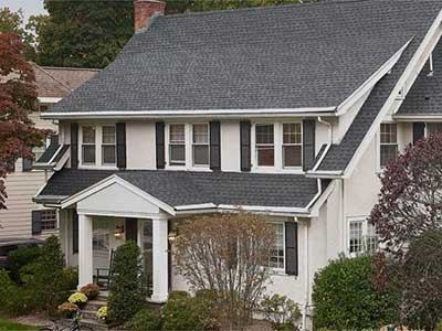 Front view of a white, mid-class home with gray GAF shingles on its roof