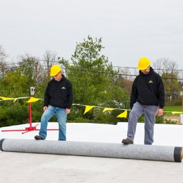 Close up of workers applying IKO brand products to commercial roof